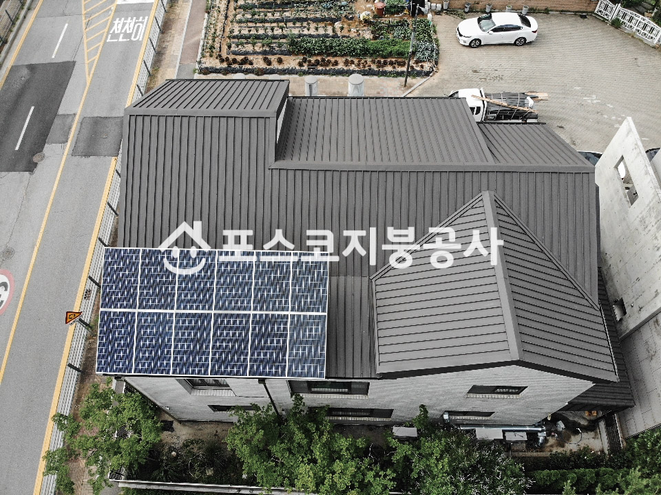 2층 주택 지붕 전체를 짙은 회색 칼라강판으로 덮은 모습